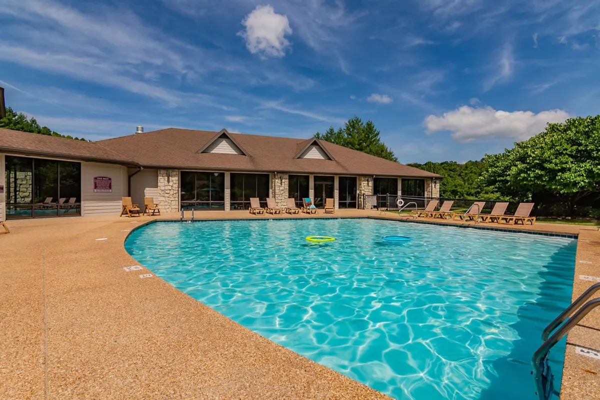 A tranquil outdoor pool area with sparkling blue water, inviting deck chairs, and lush greenery surrounding the scene. The space feels peaceful yet ideal for socializing or relaxing after a day of activities.