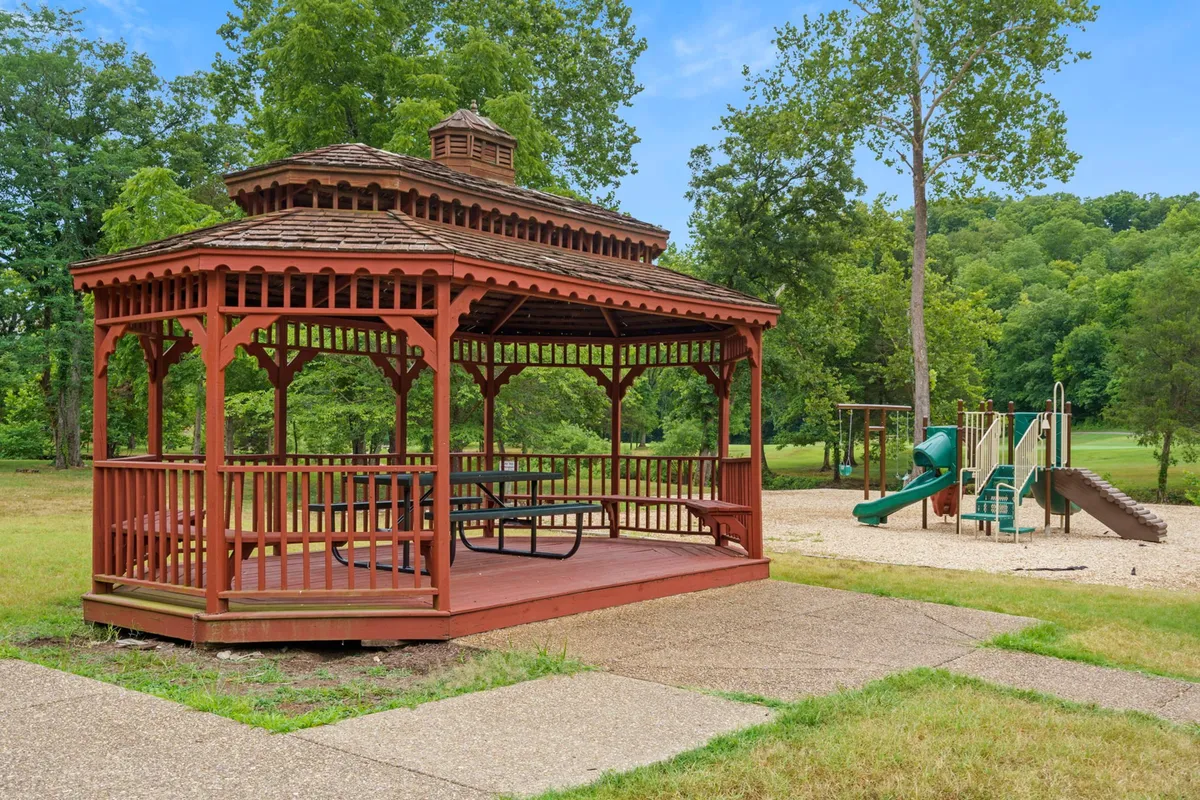 A cheerful outdoor playground with a gazebo and surrounding greenery, this image highlights spaces where families and groups can gather for picnics, celebrations, or relaxed afternoons. The playground equipment suggests fun for kids, while the gazebo provides a communal spot for adults to socialize or supervise.