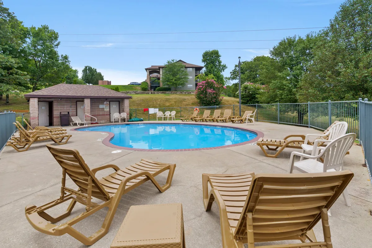 A sparkling outdoor swimming pool surrounded by lounge chairs and landscaped greenery, with a cabana area for shade. The scene is bright and inviting, suggesting a lively atmosphere perfect for families to relax, splash, and socialize during the summer season.