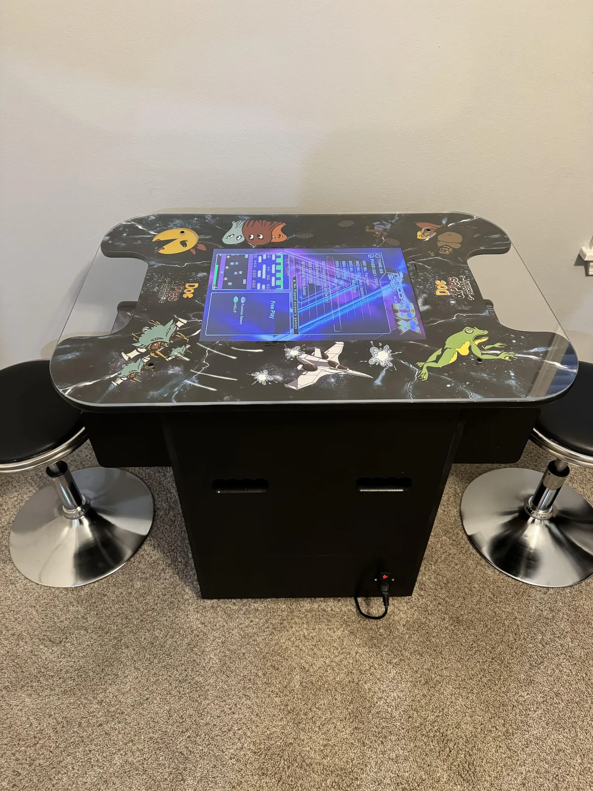 A dedicated gaming area featuring a classic arcade table, colorful wall art, and a high-tech screen. The setup invites friendly competition and fun, appealing to both kids and nostalgic adults alike.