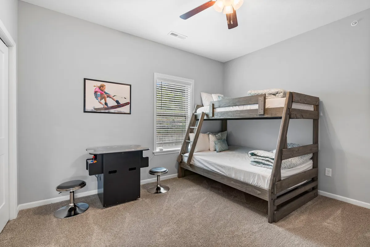 A cheerful bunk room outfitted with a twin-over-full bunk bed, a small table for play or reading, and playful decor touches. The space is inviting for children or groups, balancing functionality with comfort.